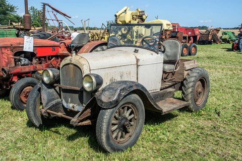 Older automobile converted into agricultural tractor at exhibition on old-fashioned harvest