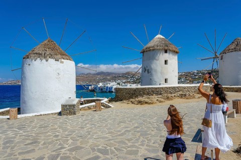 Mykonos, Cyclades, Greece - Tourists photograph the six sixteenth-century windmills lined up on a