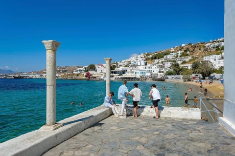 Mykonos, Cyclades, Greece - Young people on the small town beach Paralia Cheras Mikonou right at