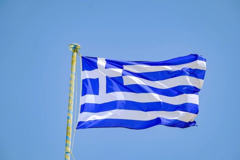Ano Mera, Mykonos, Cyclades, Greece - Greek national flag fluttering on the flag pole on the roof
