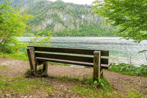Park bench standing beside beside and with view onto Lake Offensee on a cloudy day in spring,