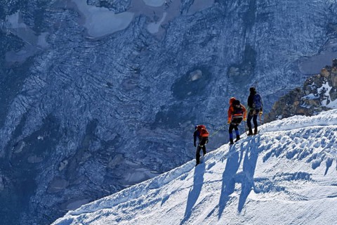 Three ascended mountaineers run across a snow-covered mountain ridge, Aiguille du Midi,