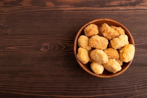 Fried crispy Chicken Nuggets on brown wooden background. top view, flat lay, copy space