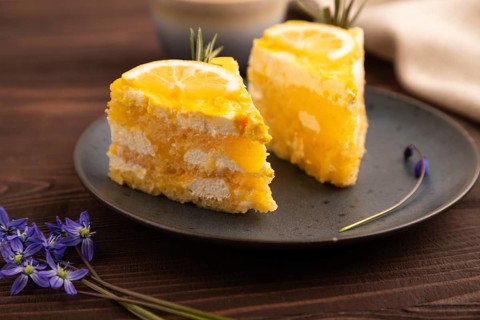 Lemon cake on brown wooden background and linen textile, cup of coffee, side view, close up,