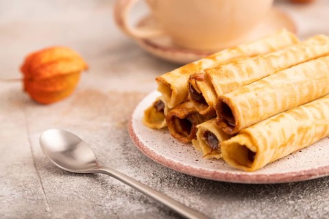 Waffles with caramel on brown concrete background and orange linen textile, cup of coffee, side