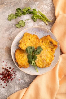Fried crispy Chicken pancakes on brown concrete background and orange linen textile. top view, flat