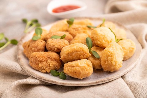 Fried crispy Chicken Nuggets with ketchup, microgreen on brown concrete background and linen