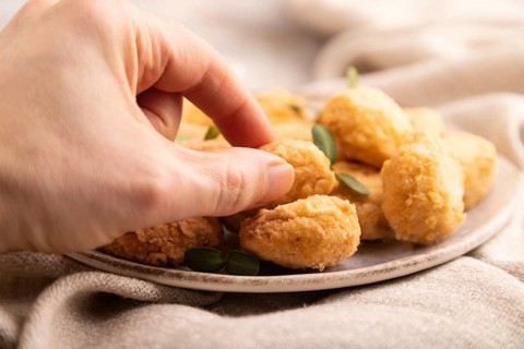 Fried crispy Chicken Nuggets with ketchup, microgreen on brown concrete background and linen