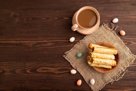 Waffles with caramel on brown wooden background and linen textile, cup of coffee, top view, flat