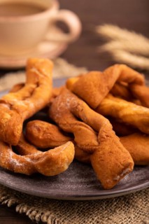 Crunchy biscuit Brushwood cookies sprinkled with powdered sugar on brown wooden background and