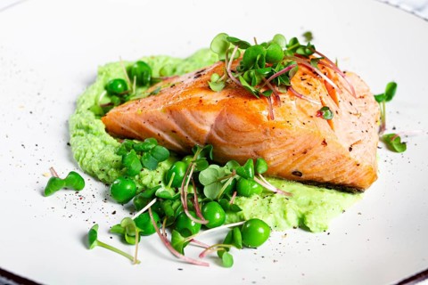 Delicious grilled salmon is placed elegantly on creamy green pea puree. Fresh microgreens and peas