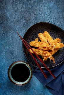 Shrimp in tempura, deep fried, on a black plate, with soy sauce, close-up, top view, no people