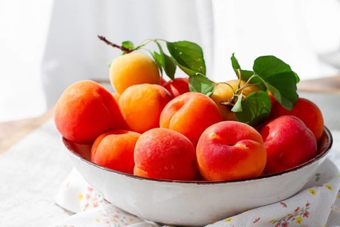 Fresh apricots in a bowl, on a bright table, natural light, top view, no people