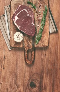 Raw steak, beef steak, rib eye steak, on a cutting board, freshly frozen, with spices and herbs, on