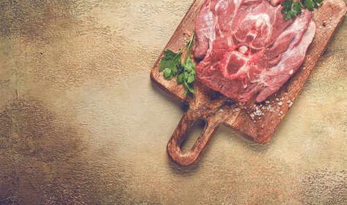 Raw steak, veal neck on the bone, fresh meat, on a cutting board, with spices, top view, without