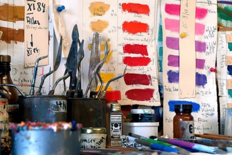 Studio with various color samples and painting supplies, creative atmosphere with strong shades,