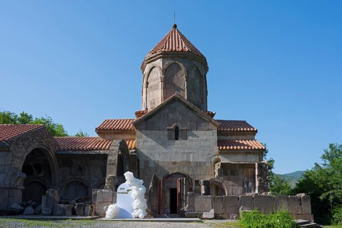 Historic church with tiled roof and blue sky in the background surrounded by greenery, Wahanavank