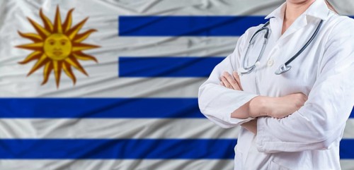 Doctor with crossed arms on Uruguay flag. Uruguay health and care concept. Female doctor on Uruguay