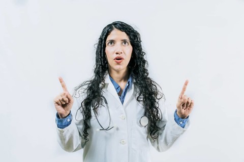 Surprised female doctor pointing up. Young female doctor looking and pointing promotion up isolated