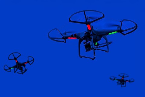 Three illuminated miniature quadcopter drones, teleoperated unmanned aerial vehicles, UAV equipped