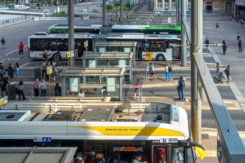 Commuters waiting for transit buses at bus stop of public transport company De Lijn at train