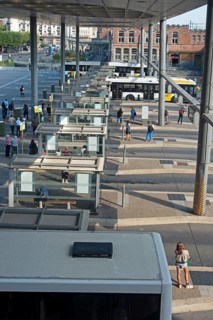 Commuters waiting for transit buses at bus stop of public transport company De Lijn at train