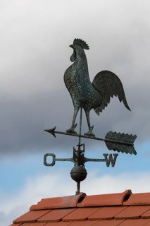 Metal weather vane with rooster on a tiled roof, blue sky and clouds, Baden-Württemberg, Germany