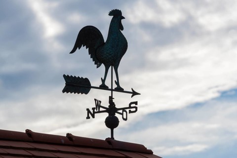 Weather vane on roof with cloudy sky looks atmospheric, Baden-Württemberg, Germany