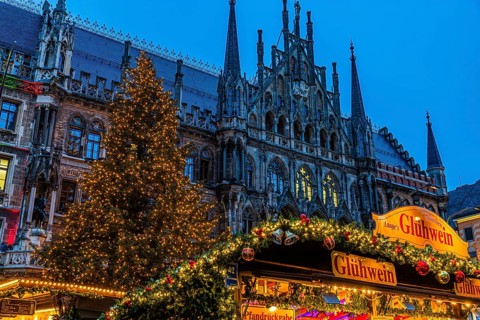 Mulled wine stand at the Christmas market, in the back the new town hall with illuminated Christmas