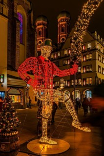 Schäffler dancers made of wire and string of lights, in the back the towers of the Church of Our