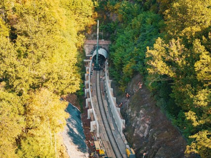 Tunneling for railroad tracks in an autumn forest area with construction workers and machines,