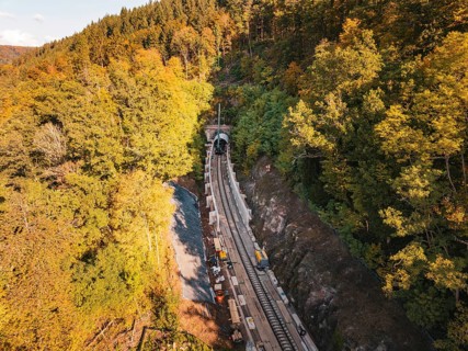 Layered view of an autumn rail construction site in the forest with construction vehicles,