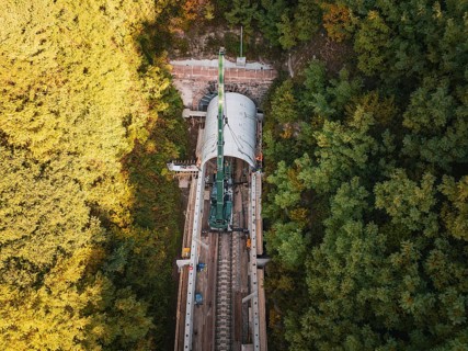 Aerial view of a construction site with a tunnel boring machine in a wooded area on railroad