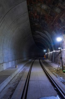 Tunnel with rails and bright lighting along the wall, dark building atmosphere, Hermann building,