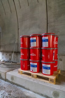 Red paint buckets on a pallet in a tunnel setting, building materials stored, building of Hermann,