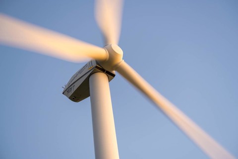 Wind turbine with rotating blades moving against a clear sky, Baden-Württemberg, Germany