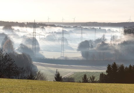 Landscape view with power poles and wind turbines in foggy morning light, Swabian Alps,
