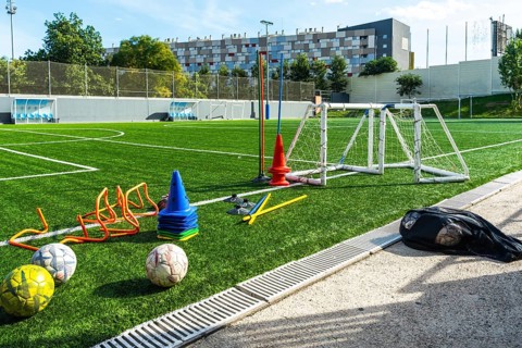 Artificial grass soccer field with multiple training equipment including cones, hurdles, a small