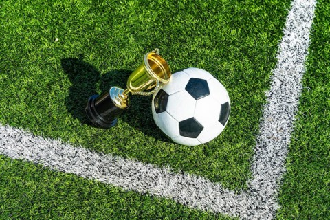 Soccer ball positioned alongside a gleaming gold trophy cup, symbolizing victory and championship