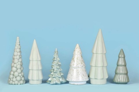 Row of different shaped light green ceramic Christmas trees on blue background