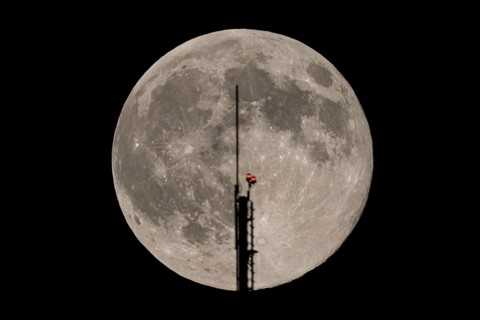 The full moon passes through the antenna on the roof of the European Central Bank (ECB), Frankfurt