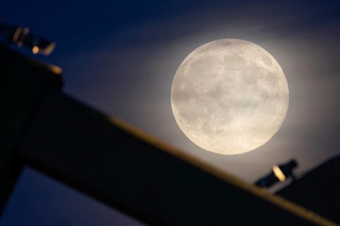 The full moon sweeps along the Frankfurt evening sky and passes the pillars of the rafter bridge,