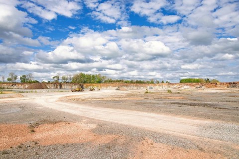 View in a limestone quarry with heavy machinery by a gravel road on a sunny summer day
