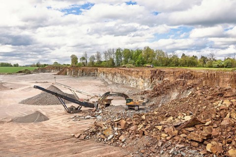 Excavator at a stone crusher with a conveyor in a quarry in a the countryside