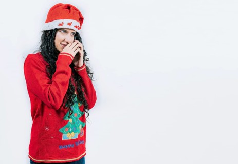 Woman in Christmas sweater secretly calling by phone. Girl in Christmas hat talking on the phone