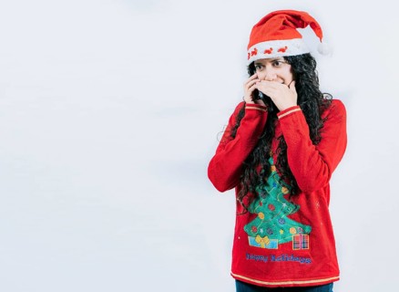 Girl in Christmas hat talking on the phone secretly. Woman in Christmas sweater secretly calling by