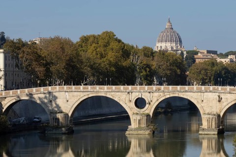 Bridge over the river Tiber with the dome of St. Peter's Basilica in the Vatican city in the