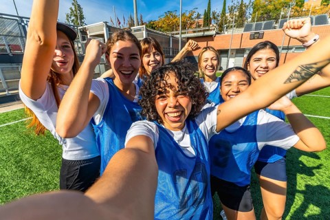 Diverse group of young women soccer players celebrating an achievement or victory, taking a joyful