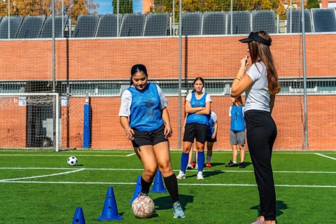 Female soccer players receiving instructions from their coach during a practice session on a green