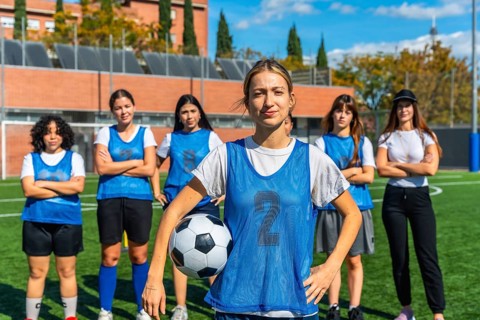 Diverse group of confident young women forming a soccer team, standing together on a green football